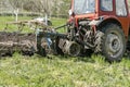 Modern red tractor machinery plowing agricultural field meadow at farm at spring autumn. Farmer cultivating and make soil tillage