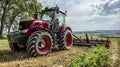Modern red tractor plowing fields under cloudy sky in scenic countryside Royalty Free Stock Photo