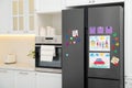 Modern refrigerator with child`s drawings, notes and magnets in kitchen. Space for text