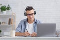 Modern remote work or education. Concentrated guy makes notes in notebook and looks at laptop