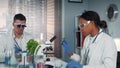In modern research laboratory black female scientist looking at organic material under microscope