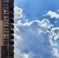 Modern residential skyscraper and beautiful blue sky and bright white clouds. White clouds on vibrant blue sky over a skyscraper. Royalty Free Stock Photo