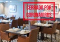Modern restaurant with tables closed and sign in spanish saying Closed due to Coronavirus