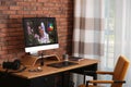 Modern retoucher`s workplace with different digital devices on wooden table near red brick wall