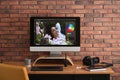 Modern retoucher`s workplace with different digital devices on wooden table near red brick wall