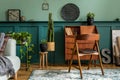 Modern and retro composition of home office interior with wooden cabinet, chair, plants, decoration.