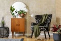 Modern retro composition of living room interior with design armchair, lamp, rattan pouf, plants, mirror, decoration, carpet.