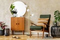 Modern retro composition of living room interior with vintage armchair, lamp, commode, tropical leaf, plant, decoration.