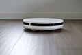 modern robot vacuum cleaner working on brown floor Royalty Free Stock Photo