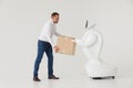 Modern Robotic Technologies. A man communicates with a robot, with cardboard box in hand. Royalty Free Stock Photo