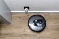 A modern robotic vacuum cleaner cleans the ceramic tiles in the bathroom next to the electric socket, an autonomous cleaning robo