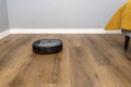 A modern robotic vacuum cleaner cleans the vinyl panels in the bedroom, an autonomous cleaning robot.