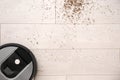 Modern robotic vacuum cleaner removing scattered buckwheat from floor, top view. Space for text