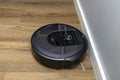 A modern robotic vacuum cleaner running on vinyl panels, an autonomous cleaning robot.