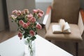 Modern room interior with armchair, book and fresh roses on table. Interior of beautiful living room decorated with flowers Royalty Free Stock Photo