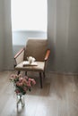 Modern room interior with armchair, book and fresh roses on table. Interior of beautiful living room decorated with flowers Royalty Free Stock Photo