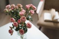 Modern room interior with armchair, book and fresh roses on table. Interior of beautiful living room decorated with flowers Royalty Free Stock Photo