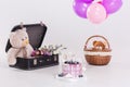 Modern round lilac birthday cake, balloons, teddy bear in vintage suitcase .