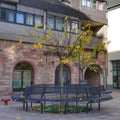 Modern round outdoor bench situated around a lush tree in an urban setting