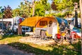 Modern round yellow gray camper with shaded terrace in the morning in camping La Ca located on the southern shore of Garda lake