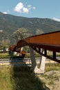 Modern rusted pedestrian and bicycle bridge with flowing Ticino river below. Beautiful panorama, immersed in the Alps of Italian Royalty Free Stock Photo