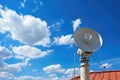 a modern satellite dish on a rooftop against blue sky