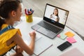 Modern schoolgirl, european teenage girl studying at home and looking at asian young teacher on laptop screen Royalty Free Stock Photo