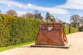 Modern sculpture of Birkin hand bag displayed in rural setting.