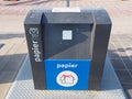 Modern semi-ground paper recycling container with a cardboard symbol on a pavement