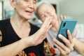 Modern senior grandmother using mobile phone,looking at cell phone screen,Waving her hands,Say Hi,talking to family while online Royalty Free Stock Photo