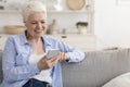 Modern Senior Woman Listening Music On Smartphone At Home, Wearing Earphones Royalty Free Stock Photo