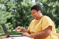 Modern senior woman using laptop outdoors and laughing candid in online meeting Royalty Free Stock Photo