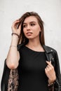 Modern sensual young woman straightens hair. Trendy attractive girl with beautiful eyes with sexy lips in a fashionable leather Royalty Free Stock Photo