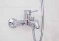 Modern silver chrome bathroom faucet with hot and cold water on a white wall. Close-up Royalty Free Stock Photo