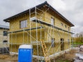 Modern single family two store home under construction, enclosed with scaffolds, thermal insulation Royalty Free Stock Photo