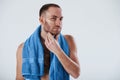 Modern skin care. Man with blue towel stands against white background in the studio Royalty Free Stock Photo