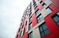 Modern skyscraper facade with red and beige composite panels and dark framed windows. The geometric pattern offers a contemporary Royalty Free Stock Photo