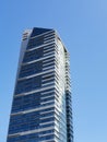 Modern skyscraper with glass facade and white stripes against blue sky, vertical Royalty Free Stock Photo