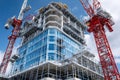 Modern skyscraper under construction with cranes and scaffolding Royalty Free Stock Photo