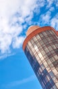 Modern skyscraper with a unique round shape, cloudy sky background, copy space Royalty Free Stock Photo