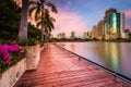 Modern skyscrapers, flowers, and palm trees along Lake Rajada at