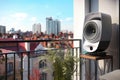 a modern sleek speaker on an apartment balcony overlooking a busy street