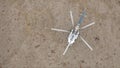 Modern small helicopter on a dried rocky field, aerial top view. Clip. Landed aircraft standing on the ground in a dry