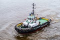 A modern small tugboat cruises in the water area of the port. Preparing to maneuver a large ship. Royalty Free Stock Photo