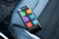 Modern smart phone with smart car app on passenger leather seat