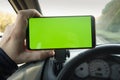 Modern smart phone with isolated green screen for mockup. The driver uses the phone on car road