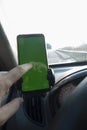 Modern smart phone with isolated green screen for mockup. The driver uses the phone on car road