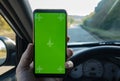 Modern smart phone with isolated green screen for mockup. The driver uses the phone on car road