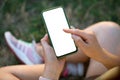 Modern smartphone device mockup. Female hands hold smartphone with empty white screen in the park