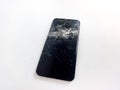 A modern smartphone with a shattered screen lies on a plain white background Royalty Free Stock Photo